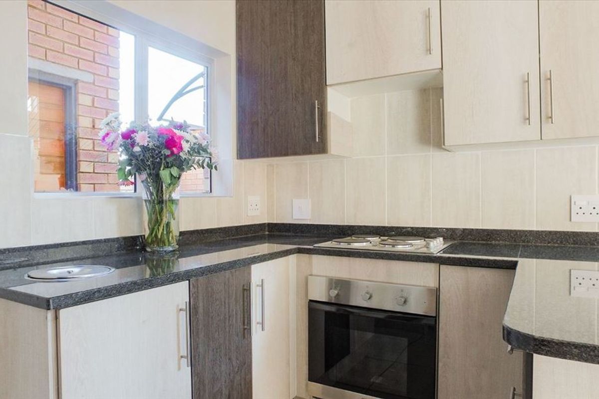 Modern kitchen featuring two-tone cabinetry, granite countertops, a built-in electric oven and hob, and a tiled backsplash.