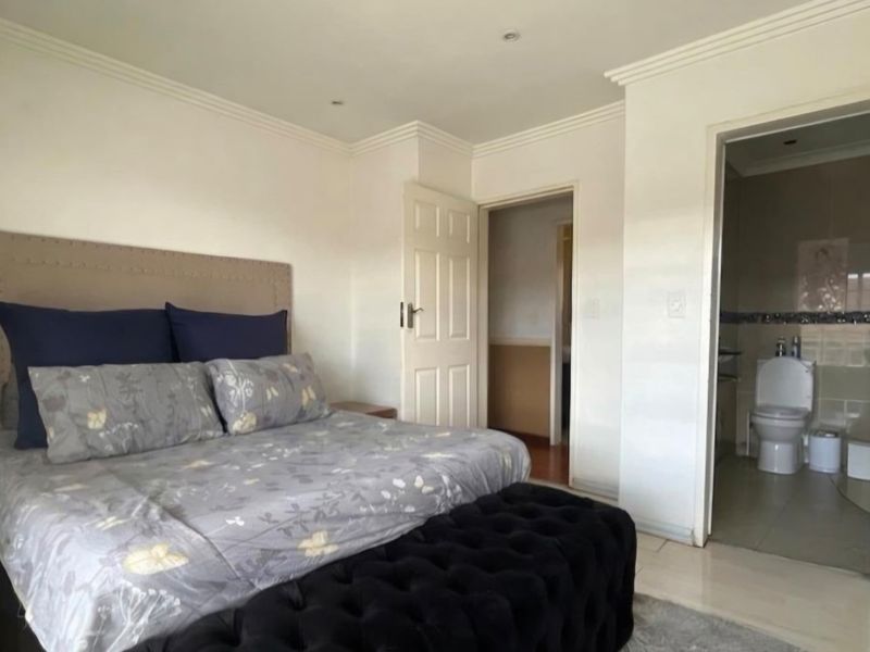 Spacious bedroom featuring an en-suite bathroom with a folding door, neutral wall finishes, and recessed ceiling lighting.
