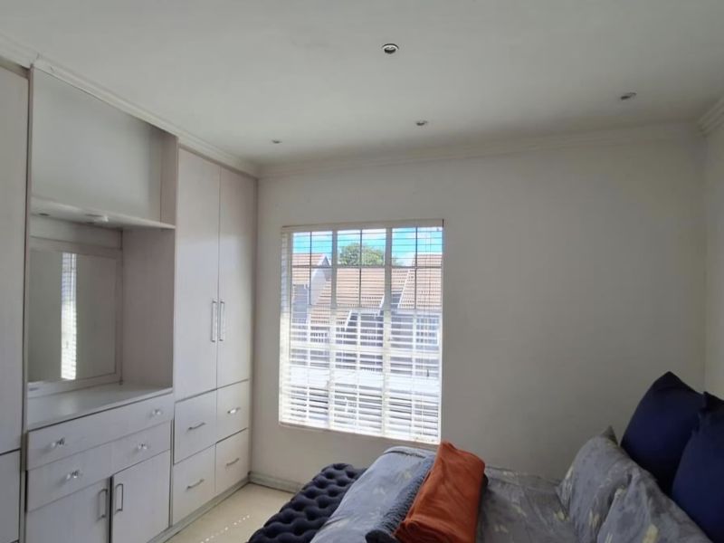 A well-maintained bedroom featuring extensive built-in cabinetry, recessed ceiling lighting, and venetian blinds, offering a clean and functional living space.