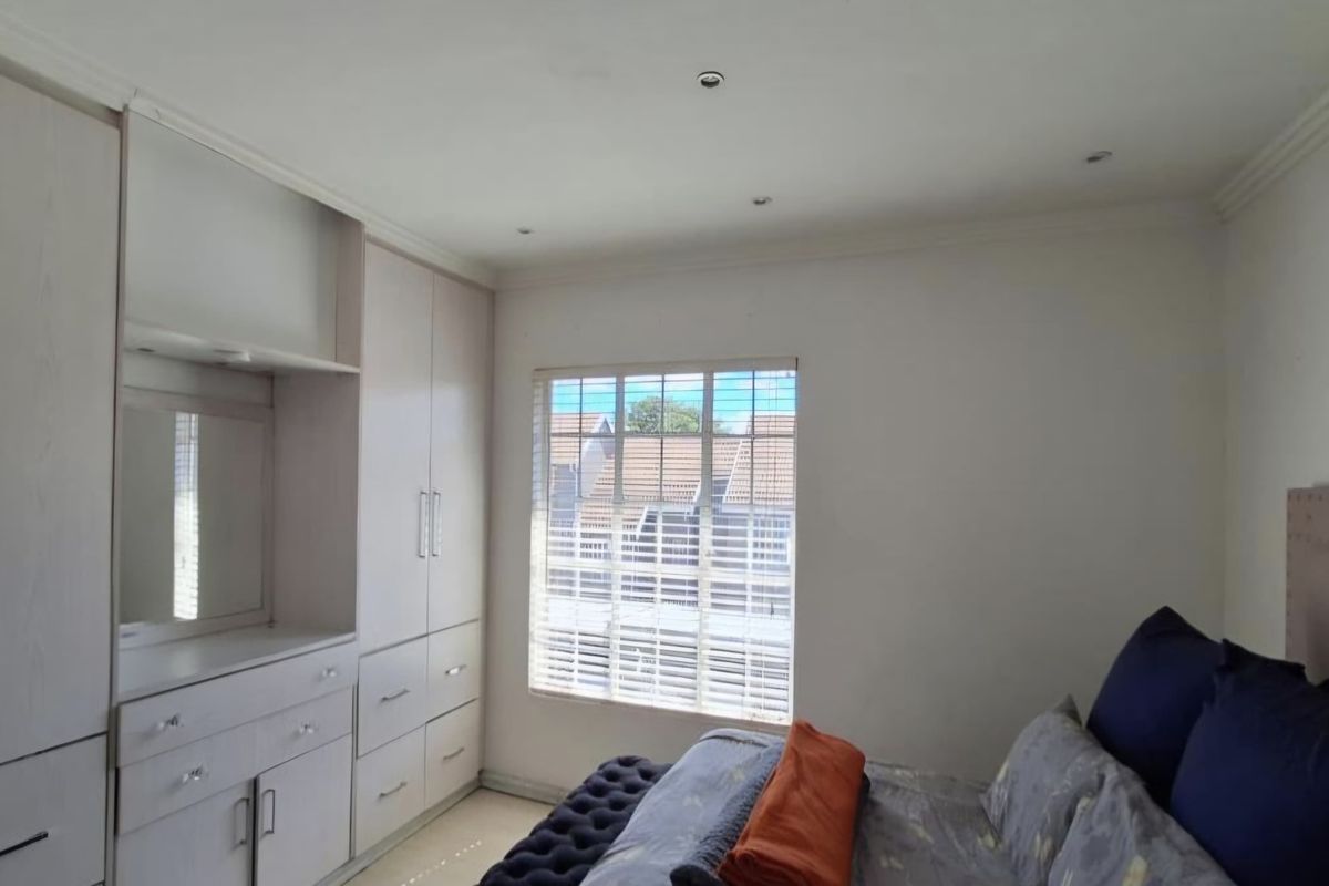 A well-maintained bedroom featuring extensive built-in cabinetry, recessed ceiling lighting, and venetian blinds, offering a clean and functional living space.