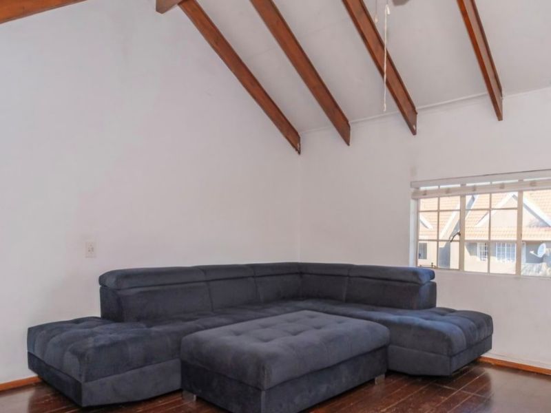 Living room featuring a high vaulted ceiling with exposed timber beams and dark timber flooring, providing a spacious and character-filled atmosphere.