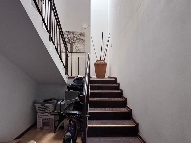 A functional interior hallway featuring a staircase with metal balustrades and tiled steps, providing access between levels.