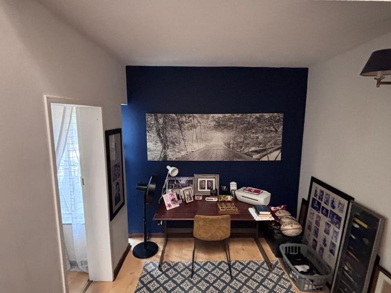 A compact home office space featuring laminate flooring and a dark blue accent wall, suitable for a dedicated workspace or study area.