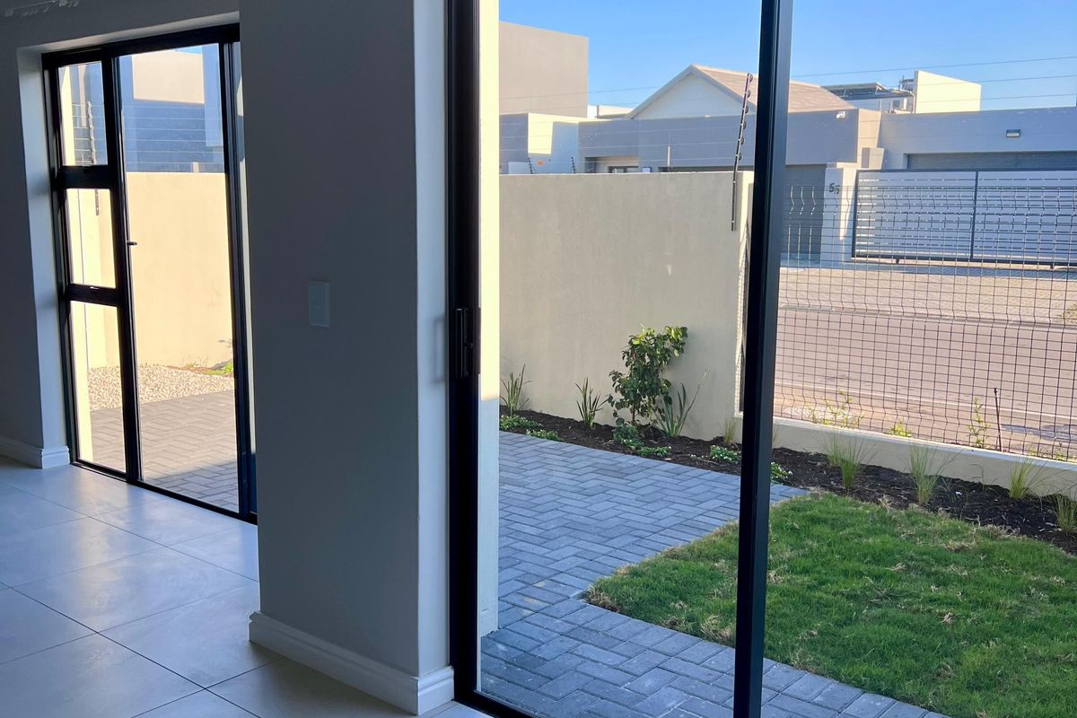 Bright, modern living area featuring large sliding glass doors that open onto a private paved patio and small garden space.