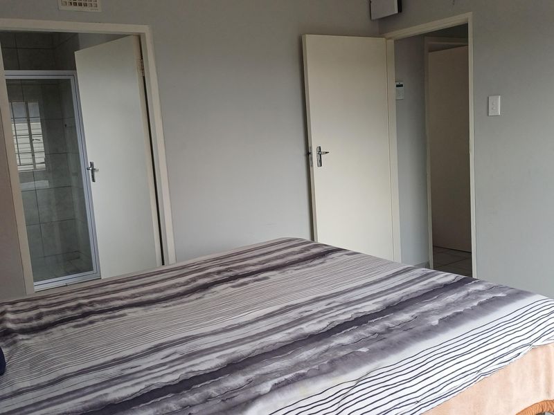 A bedroom featuring tiled flooring and an en-suite bathroom, providing a functional and neutral living space.