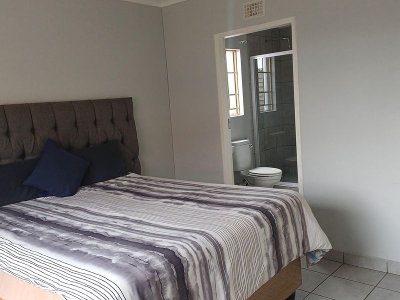 A bedroom featuring tiled flooring and an attached en-suite bathroom with a shower and toilet.