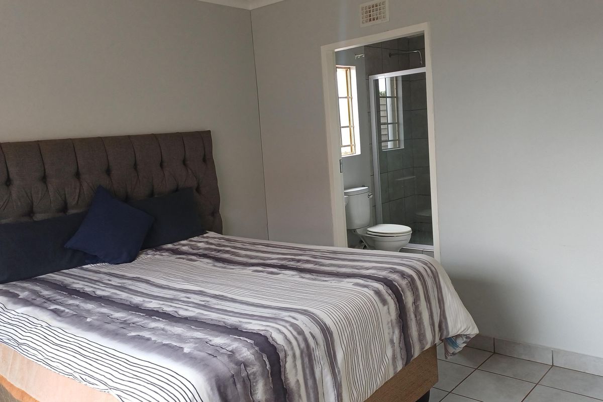 A bedroom featuring tiled flooring and an attached en-suite bathroom with a shower and toilet.