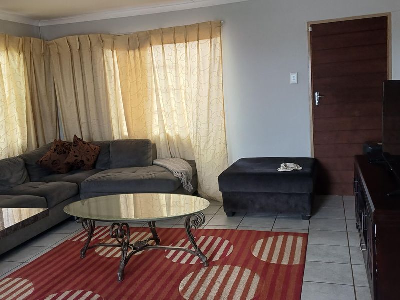 A living room featuring tiled flooring, cove cornicing, and a timber door, providing a functional and neutral space for relaxation.