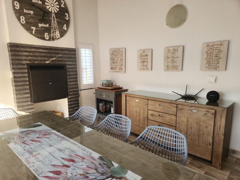 Dining area featuring a built-in fireplace with stone cladding, tiled flooring, and shutter blinds.