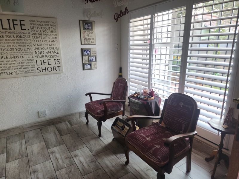 A cozy living area featuring wood-look tile flooring and white plantation shutters that provide natural light and privacy.