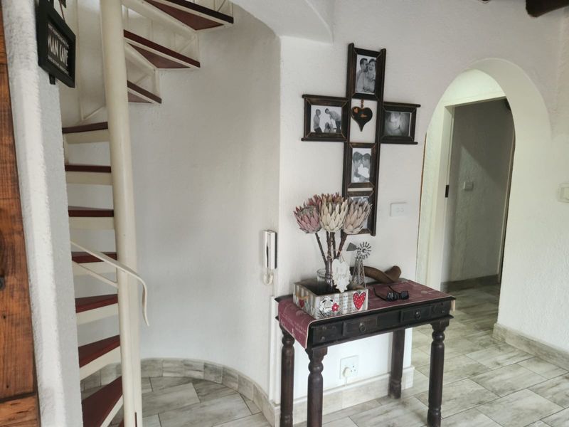 Entrance area featuring a spiral staircase, tiled flooring, and an arched doorway leading to the interior living spaces.