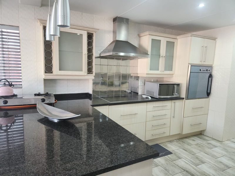 A well-maintained kitchen featuring granite countertops, built-in cabinetry, a stainless steel extractor fan, and a built-in oven with a tiled splashback.