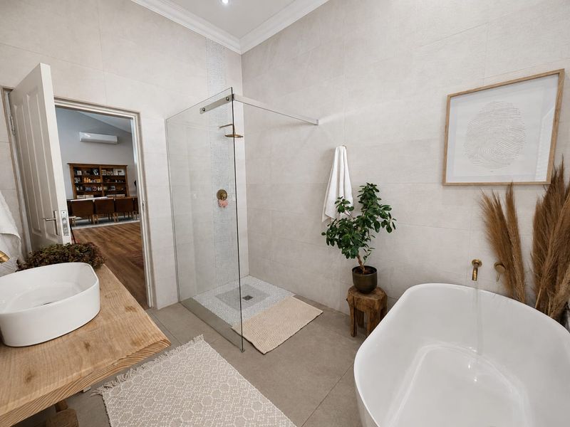 Modern bathroom featuring a walk-in shower with glass screen, a contemporary freestanding bathtub, and a vessel sink on a wooden vanity.