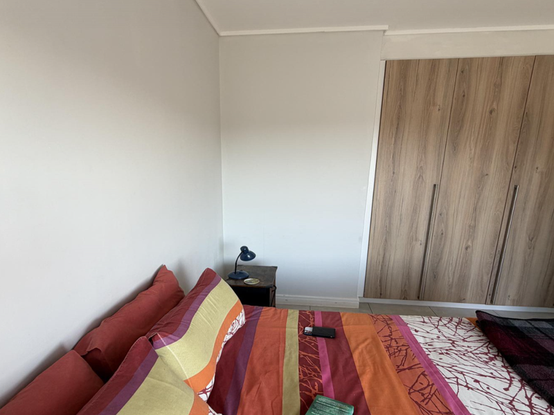 A bedroom featuring a built-in wardrobe with wood-grain finish doors and neutral wall paint.