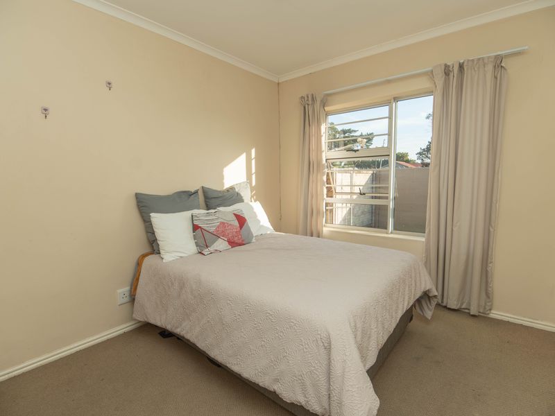 A standard bedroom featuring carpeted flooring, a louvered window, and neutral wall finishes, providing a functional space ready for personalization.