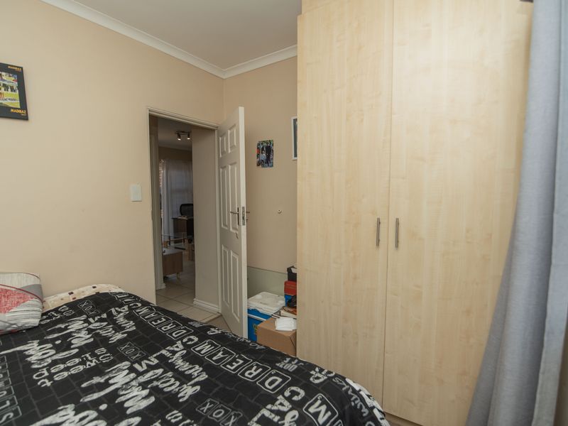 A bedroom featuring a light wood-finish built-in wardrobe and access to an adjacent room through a standard internal door.