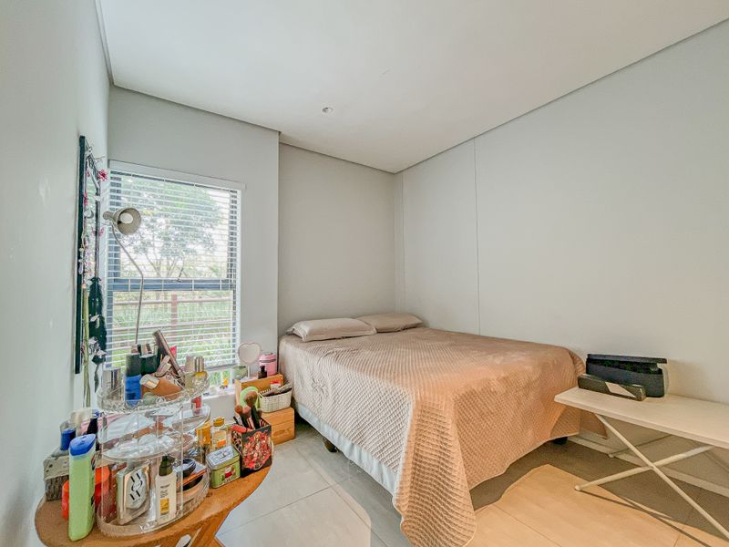 A functional bedroom featuring tiled flooring, recessed lighting, and a window fitted with venetian blinds, offering a clean and neutral living space.