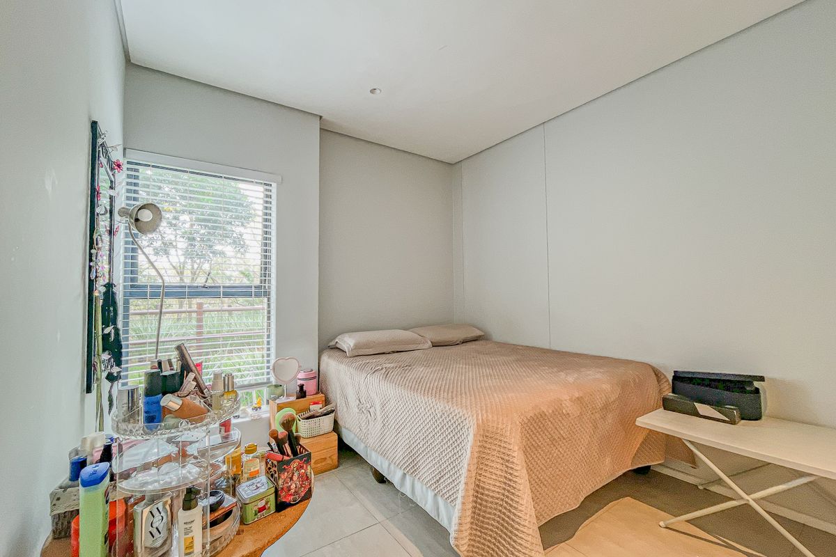 A functional bedroom featuring tiled flooring, recessed lighting, and a window fitted with venetian blinds, offering a clean and neutral living space.