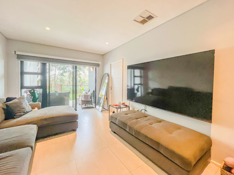 A bright living room featuring large sliding glass doors leading to a patio, tiled flooring, and recessed lighting.