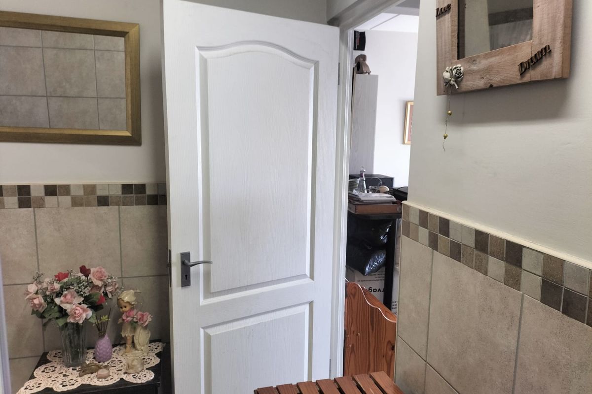 A bathroom interior featuring neutral wall tiling and a standard internal door leading to an adjacent room.