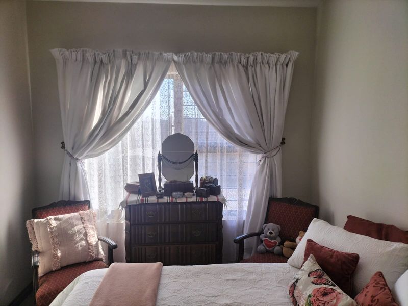 A cozy bedroom featuring a large window with curtains, providing natural light and a comfortable atmosphere.