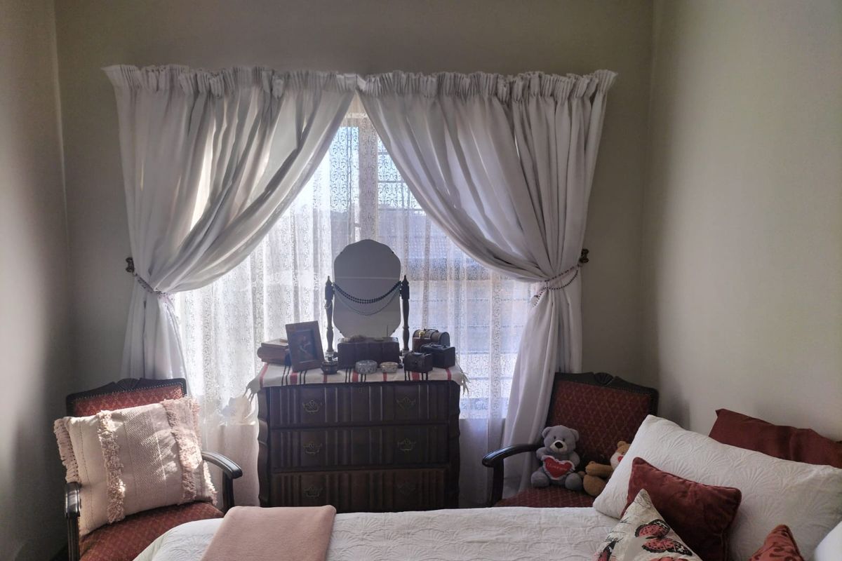A cozy bedroom featuring a large window with curtains, providing natural light and a comfortable atmosphere.