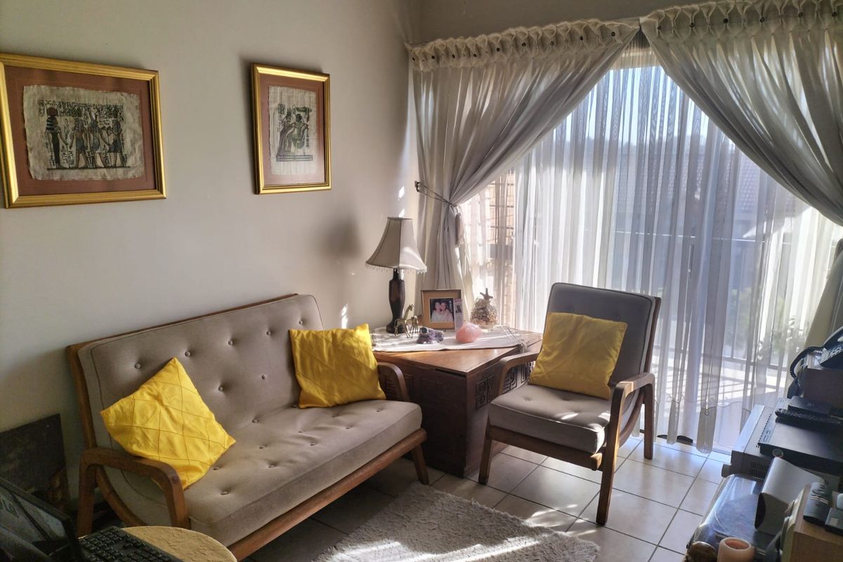 A cozy living room area featuring tiled flooring and a large sliding glass door with curtains, providing natural light and access to the balcony.