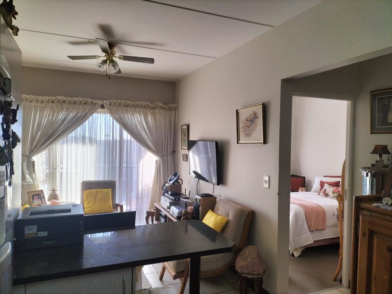 Open plan living area featuring a granite breakfast bar, ceiling fan, and direct access to a balcony, with an adjacent bedroom visible.