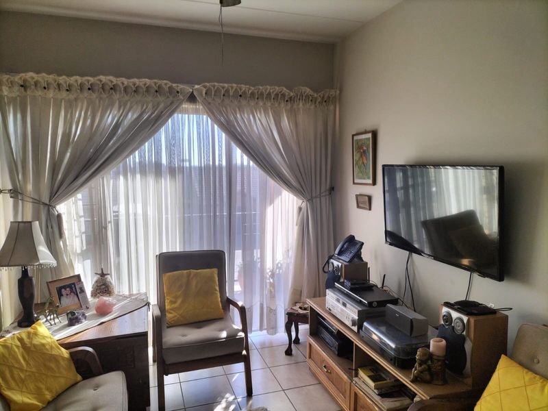 A cozy living room featuring tiled flooring and a large sliding glass door that provides access to an outdoor balcony area.