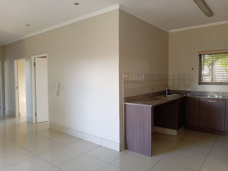 A clean, modern kitchen area featuring granite countertops, dark wood cabinetry, and neutral floor tiles, offering a functional and well-maintained space.