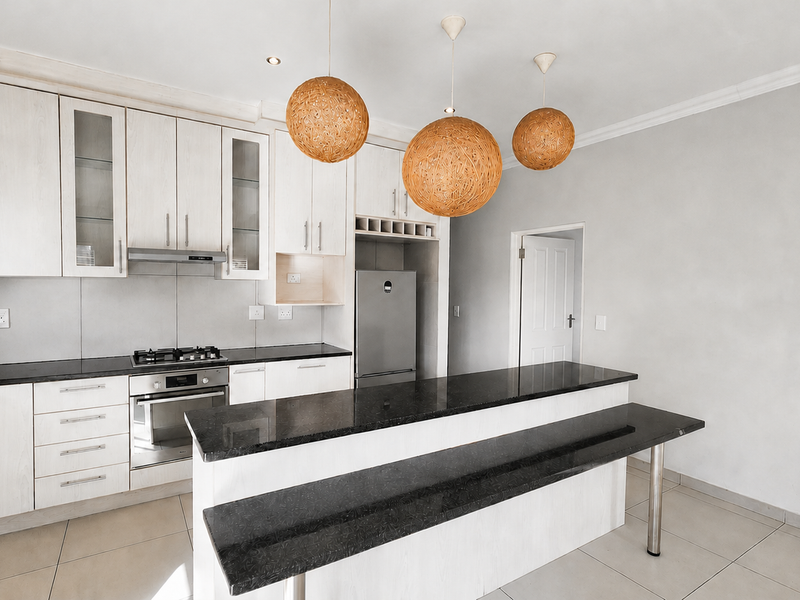 Modern kitchen featuring light wood cabinetry, granite countertops, a breakfast bar, and integrated appliances including a gas hob and oven.