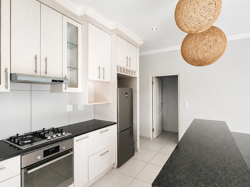 Modern kitchen featuring light wood cabinetry, granite countertops, integrated gas hob, electric oven, and a functional breakfast bar area.