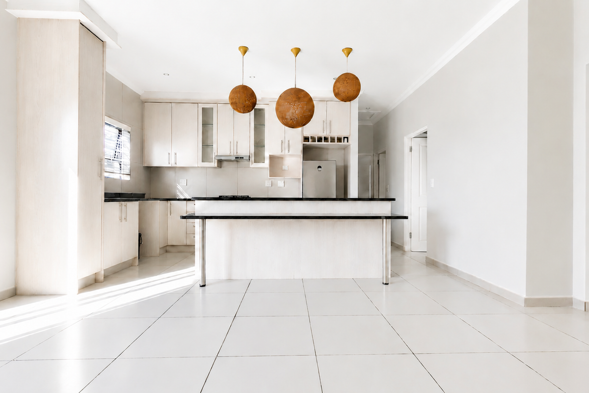 Modern open-plan kitchen featuring light wood cabinetry, stone countertops, a central island, and neutral tiled flooring in a bright, spacious layout.