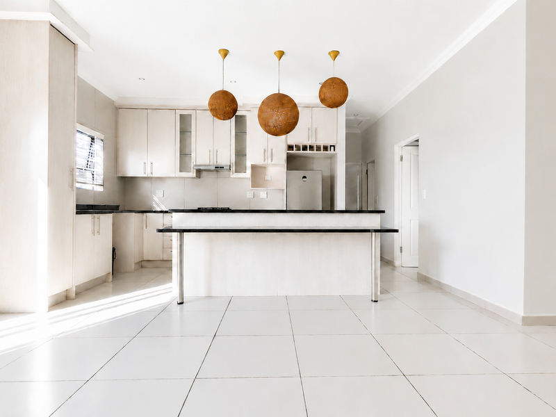 Modern open-plan kitchen featuring light wood cabinetry, stone countertops, a central island, and neutral tiled flooring in a bright, spacious layout.