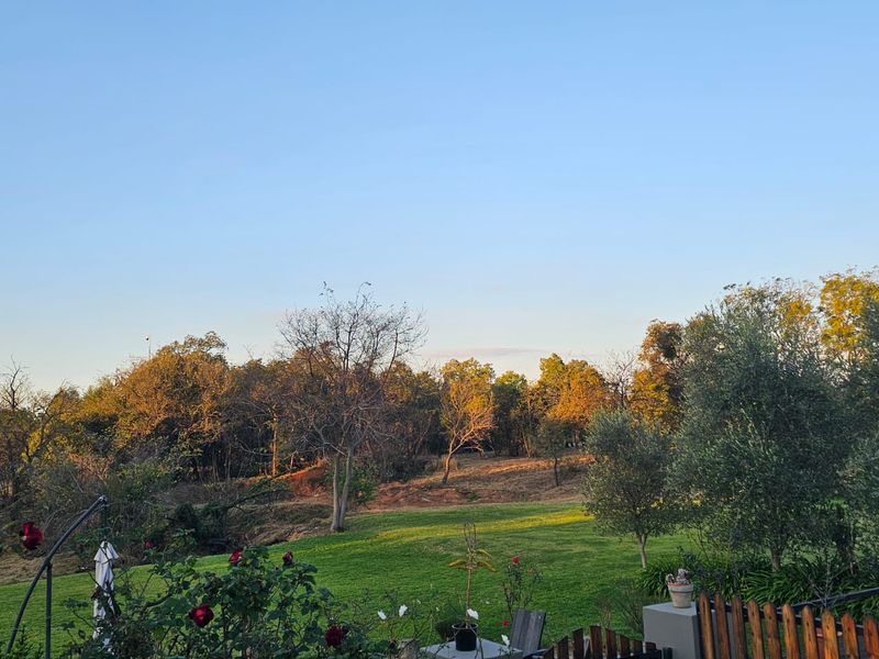 A scenic view of a lush green garden and surrounding natural landscape at sunset.