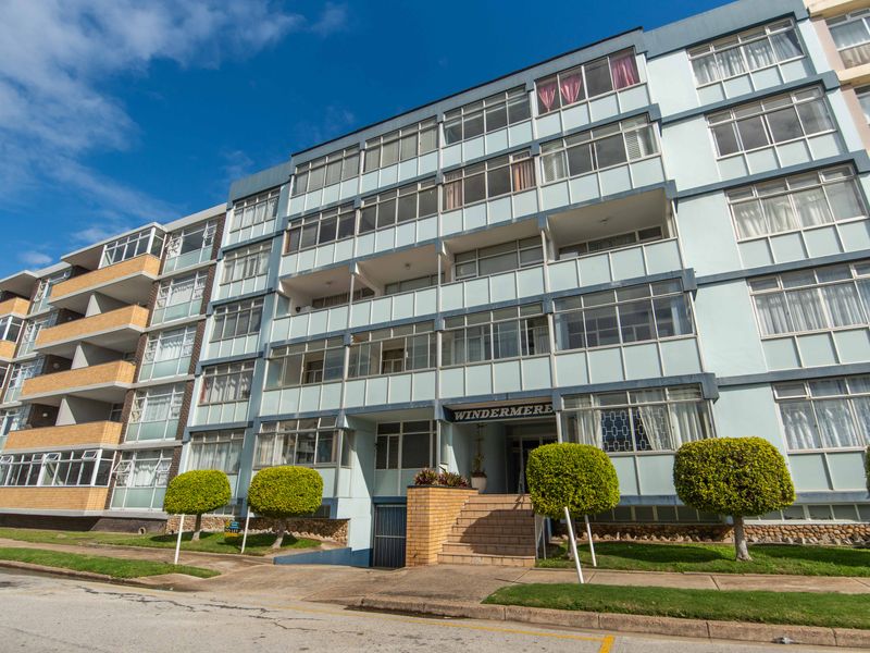Front exterior view of the Windermere apartment building, featuring a multi-story facade with enclosed balconies and a paved entrance.