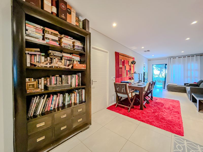 An open-plan living and dining area featuring tiled flooring, recessed downlighting, and direct access to an outdoor space.