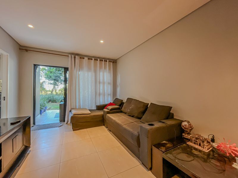 A well-lit living room featuring tiled flooring, recessed downlights, and a sliding glass door providing direct access to the outdoor area.