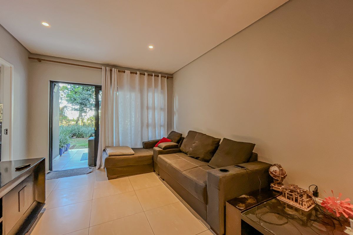 A well-lit living room featuring tiled flooring, recessed downlights, and a sliding glass door providing direct access to the outdoor area.
