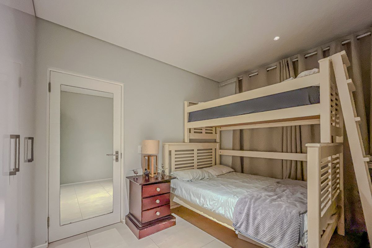 A well-maintained bedroom featuring neutral wall tones, tiled flooring, and recessed ceiling lighting, providing a clean and functional living space.