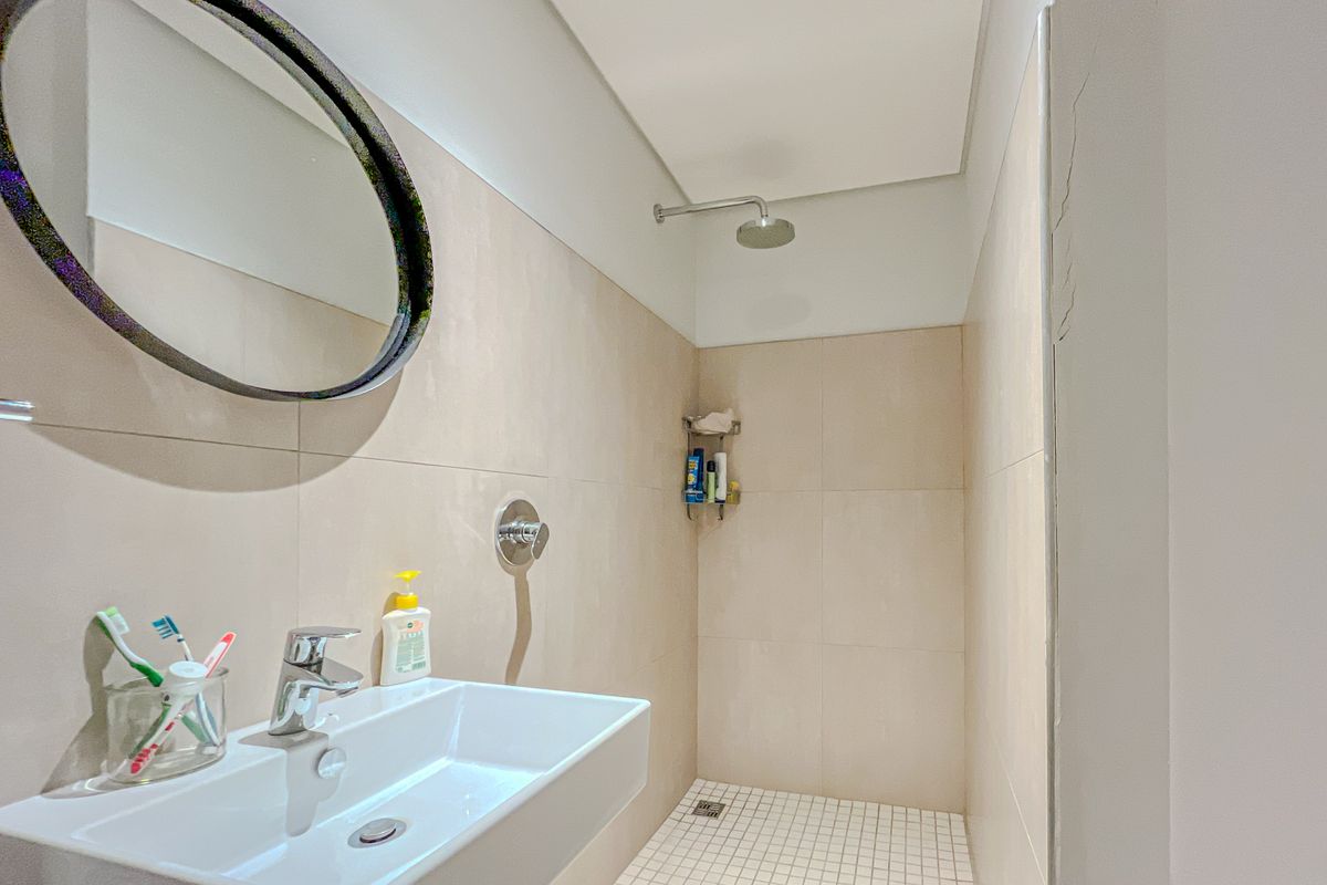 Modern bathroom featuring a wall-mounted basin, chrome fixtures, and a walk-in shower with neutral wall tiling.