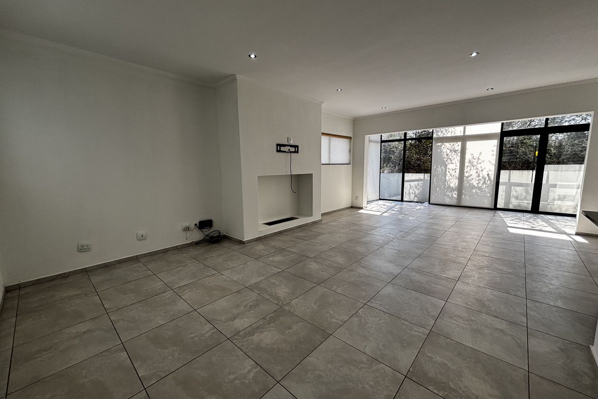Spacious, light-filled living area featuring large format floor tiles, a built-in fireplace, and expansive aluminium sliding doors leading to the exterior.