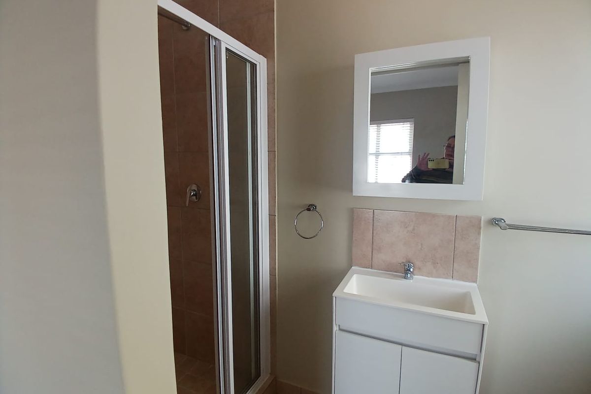 A functional bathroom featuring a shower enclosure, a white vanity cabinet with basin, and a wall-mounted mirror.
