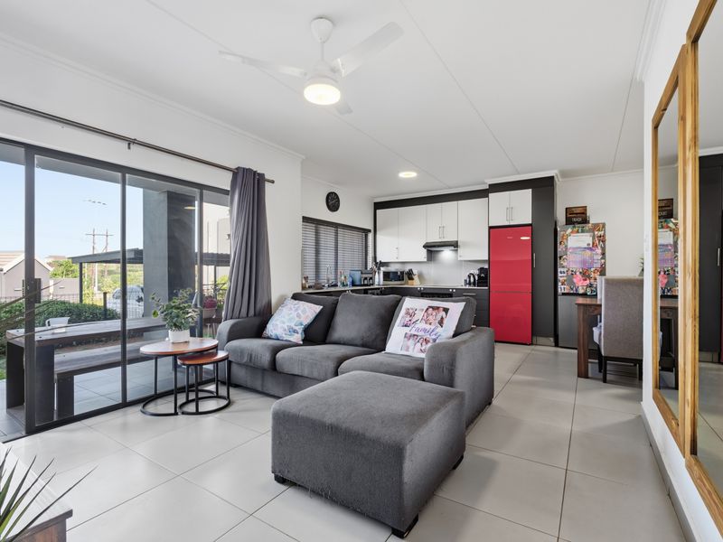 Open-plan living and kitchen area featuring tiled flooring, modern cabinetry, and large sliding glass doors providing access to the outdoor patio.