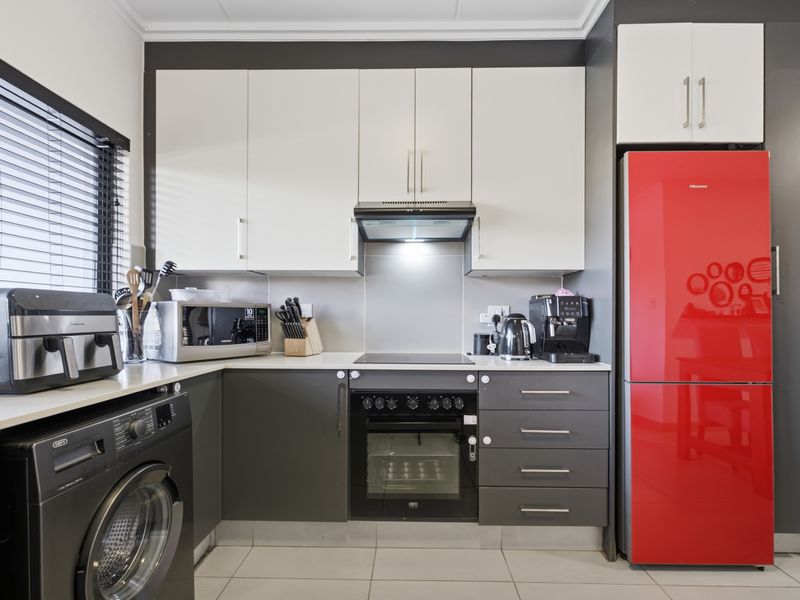 Modern kitchen featuring two-tone cabinetry, integrated oven and hob, extractor fan, and tiled flooring with a clean, functional layout.