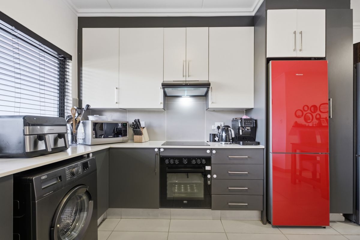 Modern kitchen featuring two-tone cabinetry, integrated oven and hob, extractor fan, and tiled flooring with a clean, functional layout.