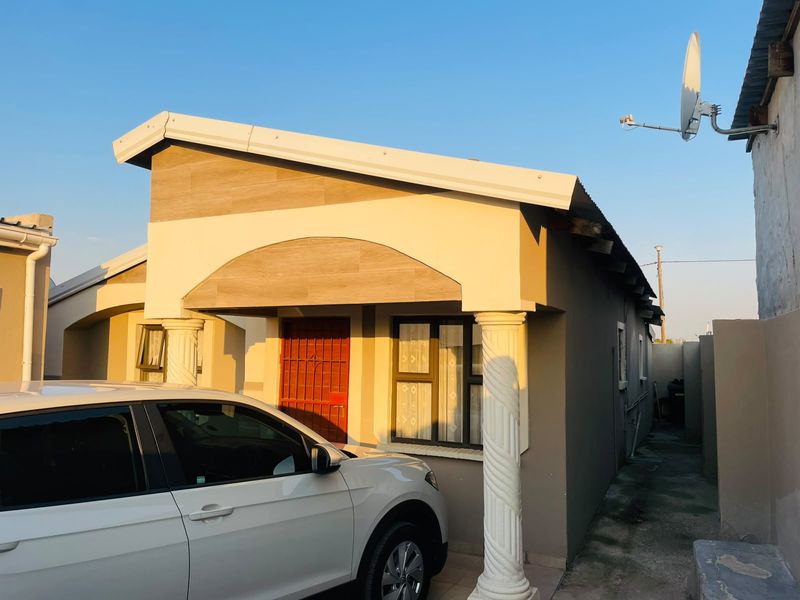 Front elevation of a residential house featuring decorative columns, a security gate, and a tiled facade accent under a pitched roof.
