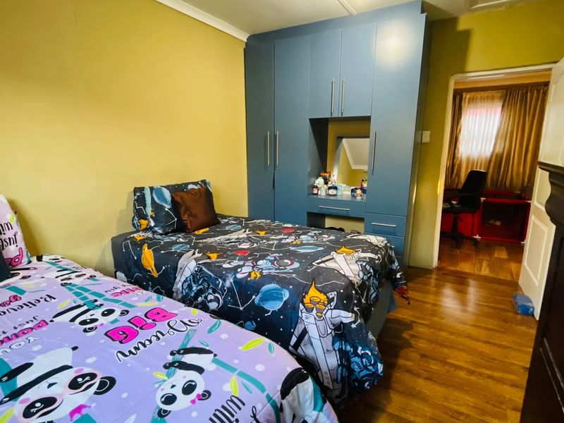 Bedroom featuring laminate flooring and a built-in wardrobe with integrated vanity area. The room requires cosmetic updates to the wall finishes.
