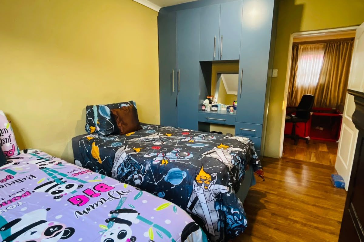 Bedroom featuring laminate flooring and a built-in wardrobe with integrated vanity area. The room requires cosmetic updates to the wall finishes.