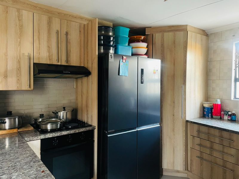 A functional kitchen featuring light wood-grain cabinetry, granite countertops, a subway tile backsplash, and integrated cooking appliances.